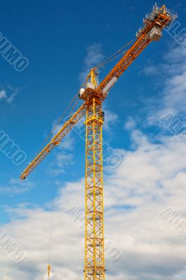 Tall white tower crane against bright blue sky.