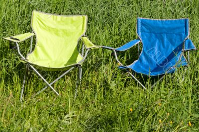Two empty folding chair on the green grass