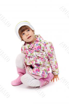 little girl in boots and a jacket sitting on the floor