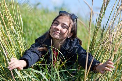 Woman in sunglasses looks through the grass with ears