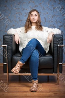 Portrait of a girl in a chair against a background of retro wall