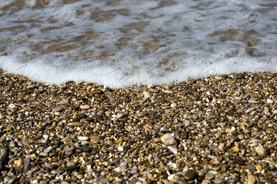 Pebbles on beach with sea wave 