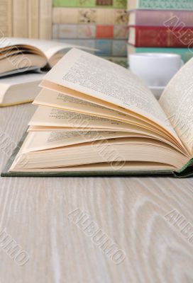 Open book on a table among other books