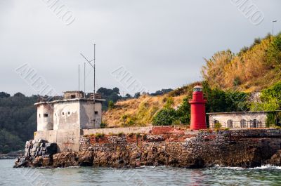small red lighthouse and old house