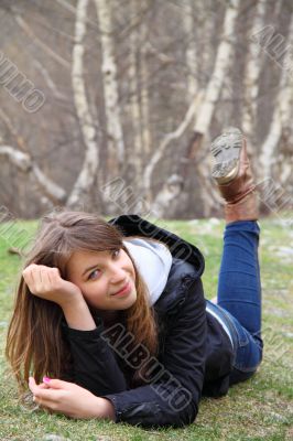 Young beautiful girl lying on the grass and smiling