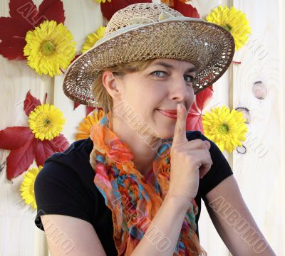 Woman in a hat shows quietly and smiles