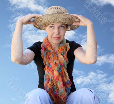  A woman in a hat on a background sky looks far
