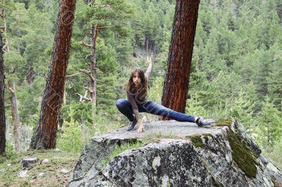 The girl on a large stone doing exercises