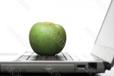 Green apple on an open laptop computer
