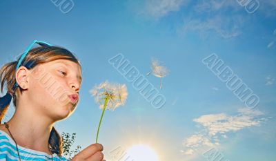 Young girl blowing dandelion
