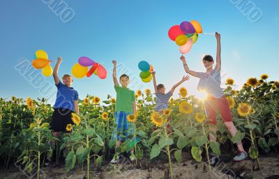 happy childrens jumping on meadow with balloons