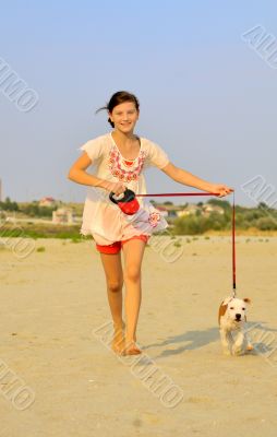 girl running with her dog on the sand 