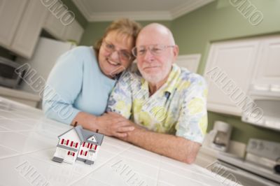 Senior Adult Couple Gazing Over Small Model Home on Counter