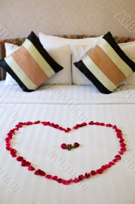 Heart of rose petals laid out on the bed