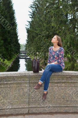 eautiful girl sits on an old stone bridge 