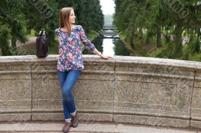 Beautiful young girl on the old stone bridge