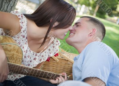 Mixed Race Couple with Guitar Kissing in the Park