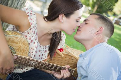 Mixed Race Couple with Guitar Kissing in the Park