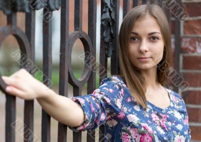 Portrait of a beautiful girl near the old rusty wrought fence