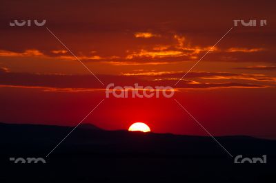 The red sunset sky with the sun and clouds