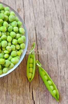 Fresh green peas on an old wooden background