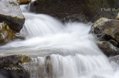 Cascade falls over mossy rocks 
