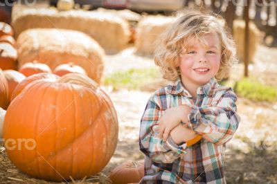 Little Boy Sitting and Holding His Pumpkin at Pumpkin Patch