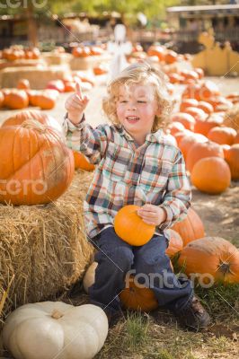 Little Boy Sitting and Holding His Pumpkin at Pumpkin Patch