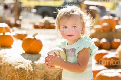 Adorable Baby Girl Holding a Pumpkin at the Pumpkin Patch
