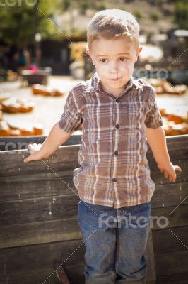 Little Boy Standing Against Old Wood Wagon at Pumpkin Patch