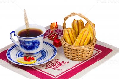 Cup of tea , candies and cakes in a wicker basket.