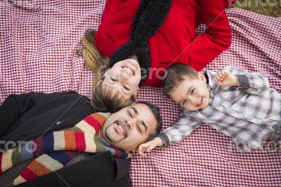 Family in Winter Clothing Laying on Their Backs in Park