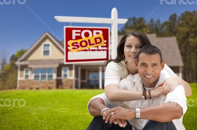 Hispanic Couple, New Home and Sold Real Estate Sign