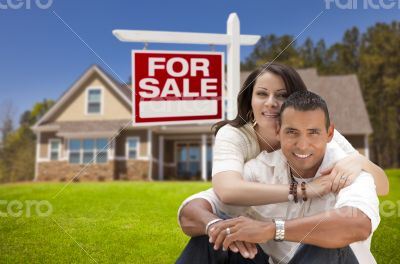 Hispanic Couple, New Home and For Sale Real Estate Sign