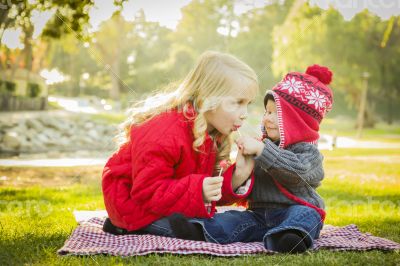 Little Girl with Baby Brother Wearing Coats and Hats Outdoors