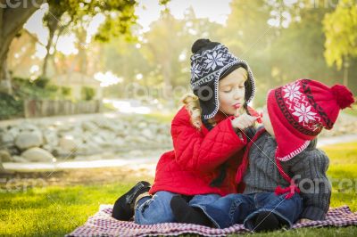 Little Girl with Baby Brother Wearing Coats and Hats Outdoors