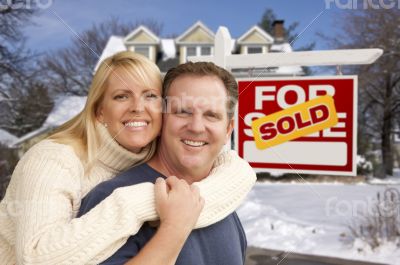 Couple in Front of New House and Real Estate Sign