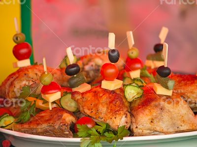 Fried chicken legs on a plate decorated with vegetables and herb