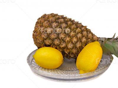Pineapple and lemons on a platter on a white background.