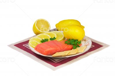 Salmon fillet and lemons on a platter on a white background.