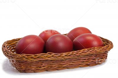 Red Easter eggs in a basket on a white background.