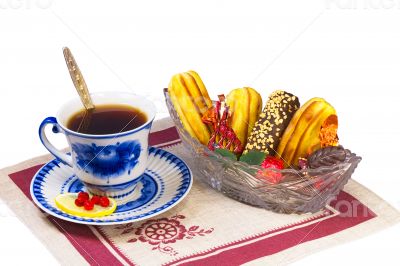 Cup of tea , candies and cakes in a wicker basket.