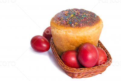 Red Easter eggs and Easter bread in a basket on a white backgrou