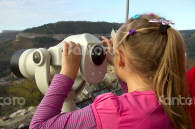 Girl looks into the distance through a telescope