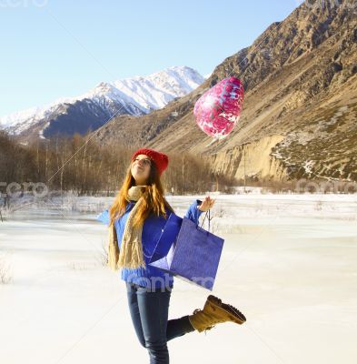 Happy girl with a balloon and a package with a gift on the backg