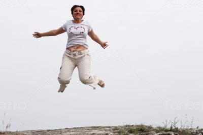 Adult smiling woman in white jumping outdoor