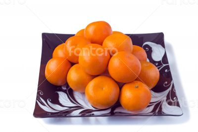 Large ripe tangerines in a glass dish on a white background.