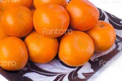 Large ripe tangerines in a glass dish on a white background.