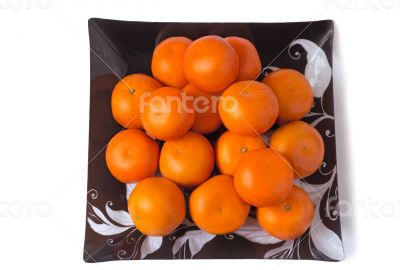 Large ripe tangerines in a glass dish on a white background.