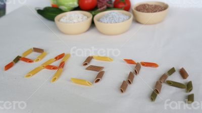 Word PASTA with vegetables and cereals in the background